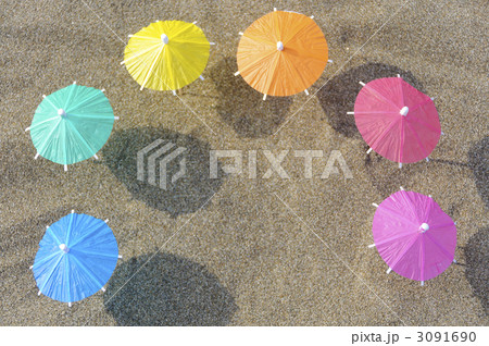 パラソル ミニチュア ビーチパラソル カラフル 波 砂 砂浜の写真素材