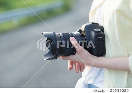 女性 一眼レフ カメラ 持つの写真素材