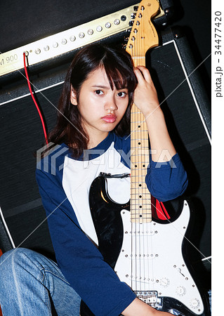 女性 若者 ギター 抱えるの写真素材