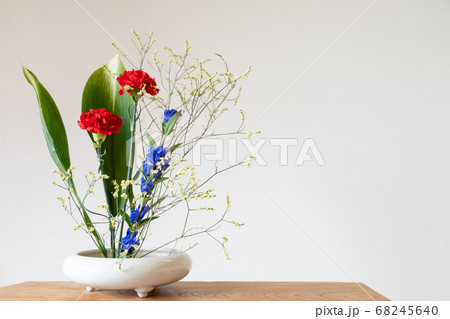 赤いカーネションと青のリンドウの生花のある室内の写真素材