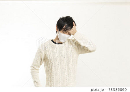 マスク姿の男性/頭痛で頭を抱える/具合が悪い独身男性/	