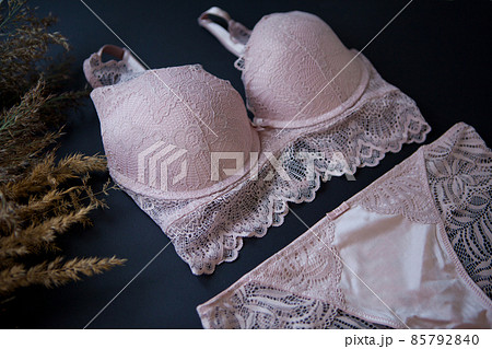 woman pink lace bra, panties lingerie near pampas grass on black