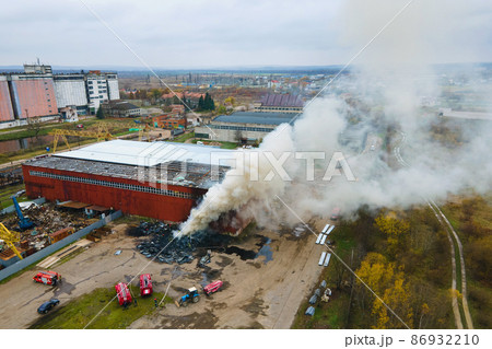 Aerial view of firefighters extinguishing fire in industrial area.