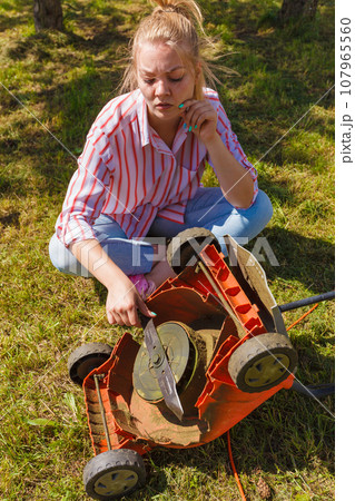 A Young White Man in a Straw Hat is Mowing a Lawn with a Lawn
