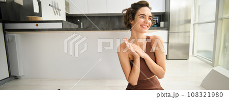 Cute brunette woman lying on yoga mat at home, doing fitness